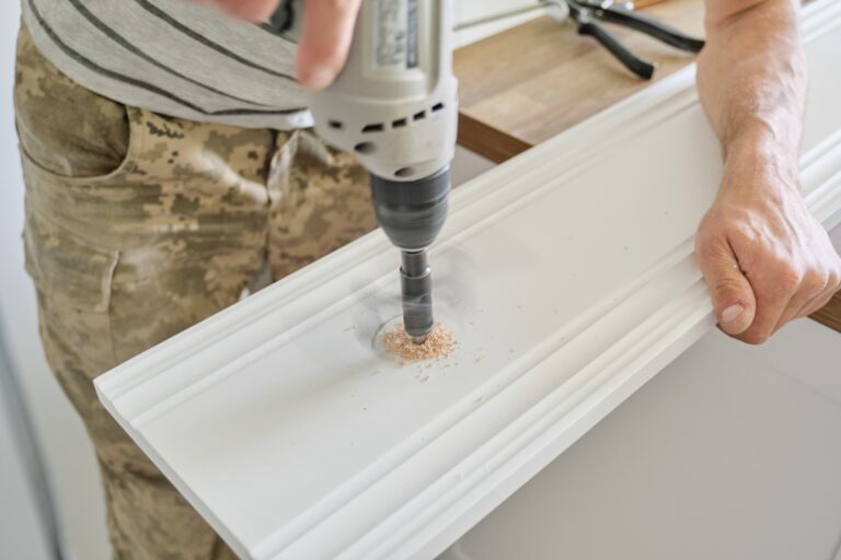 Close-up of carpenters hand using professional woodworking electric tools when working with wood. Male carving hole in wooden panel board, carpentry, woodwork, profession, people.