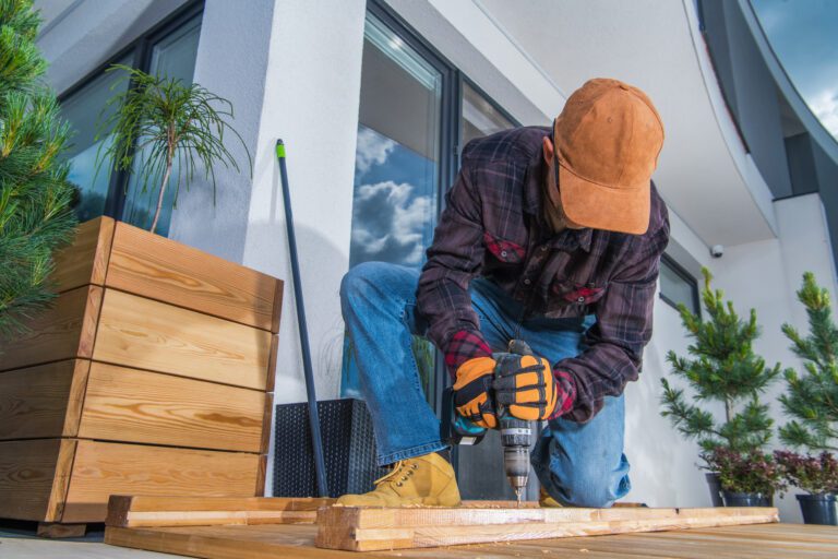 Caucasian Men and His Backyard Woodwork Project. Using Cordless Drill Driver to Attache Planks. Wood Deck Building.