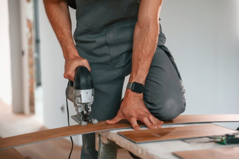 On the table. Cutting planks by the drill. Man is installing new laminated wooden floor.